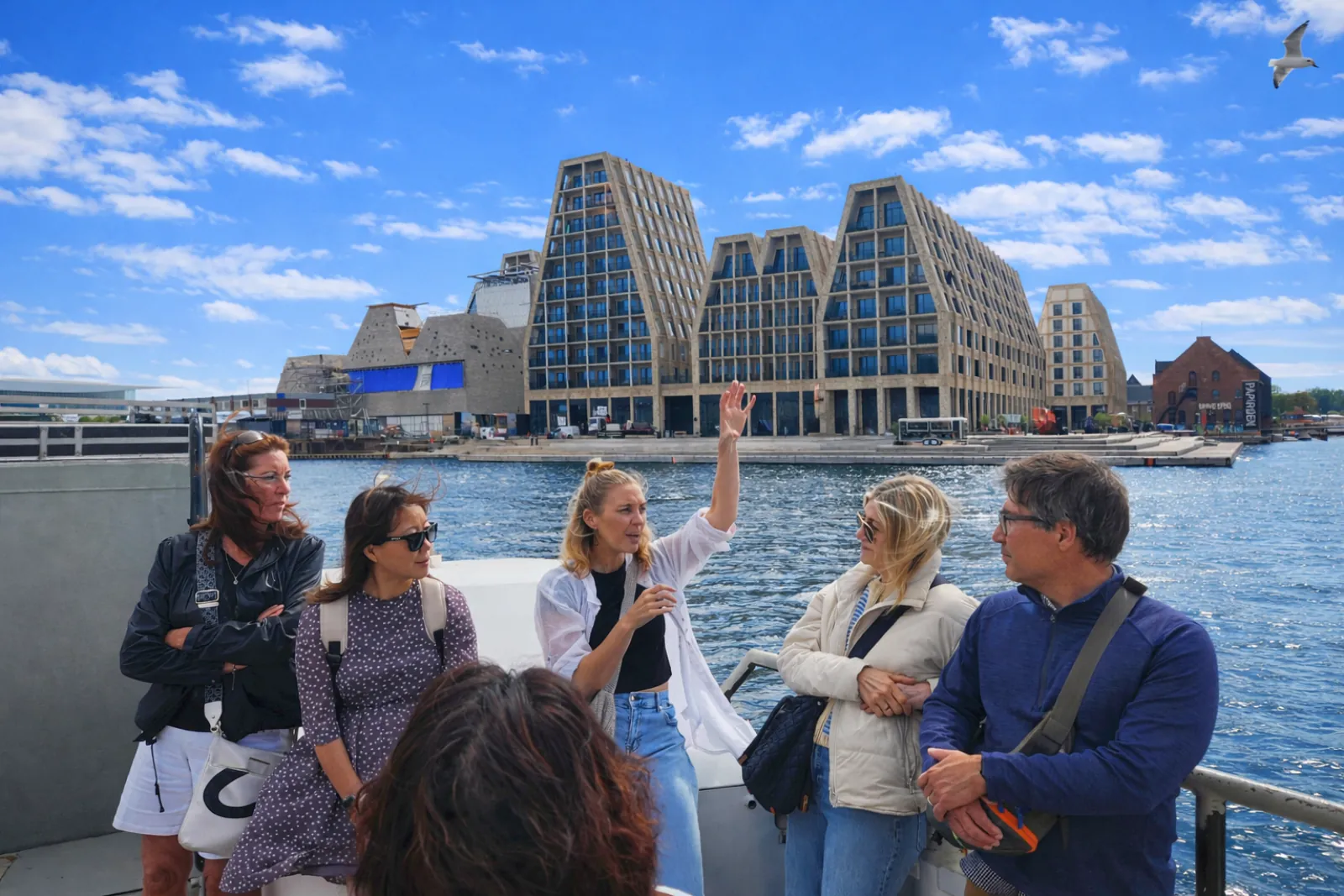 The group on the ferry with modern waterfront buildings behind