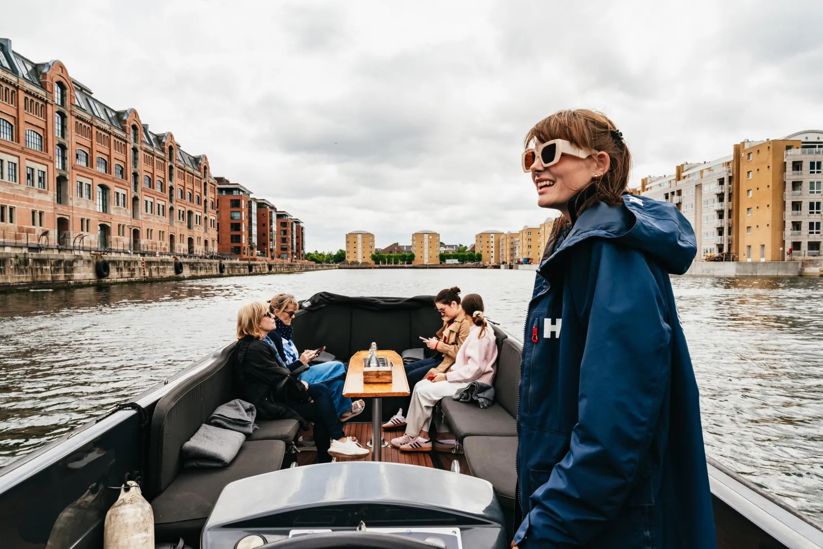 A guest smiling at the bow of the boat in a canal of modern flats