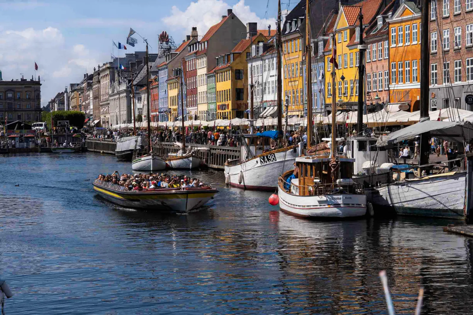 Canal boats moored beneath the coloured townhouses of Nyhavn