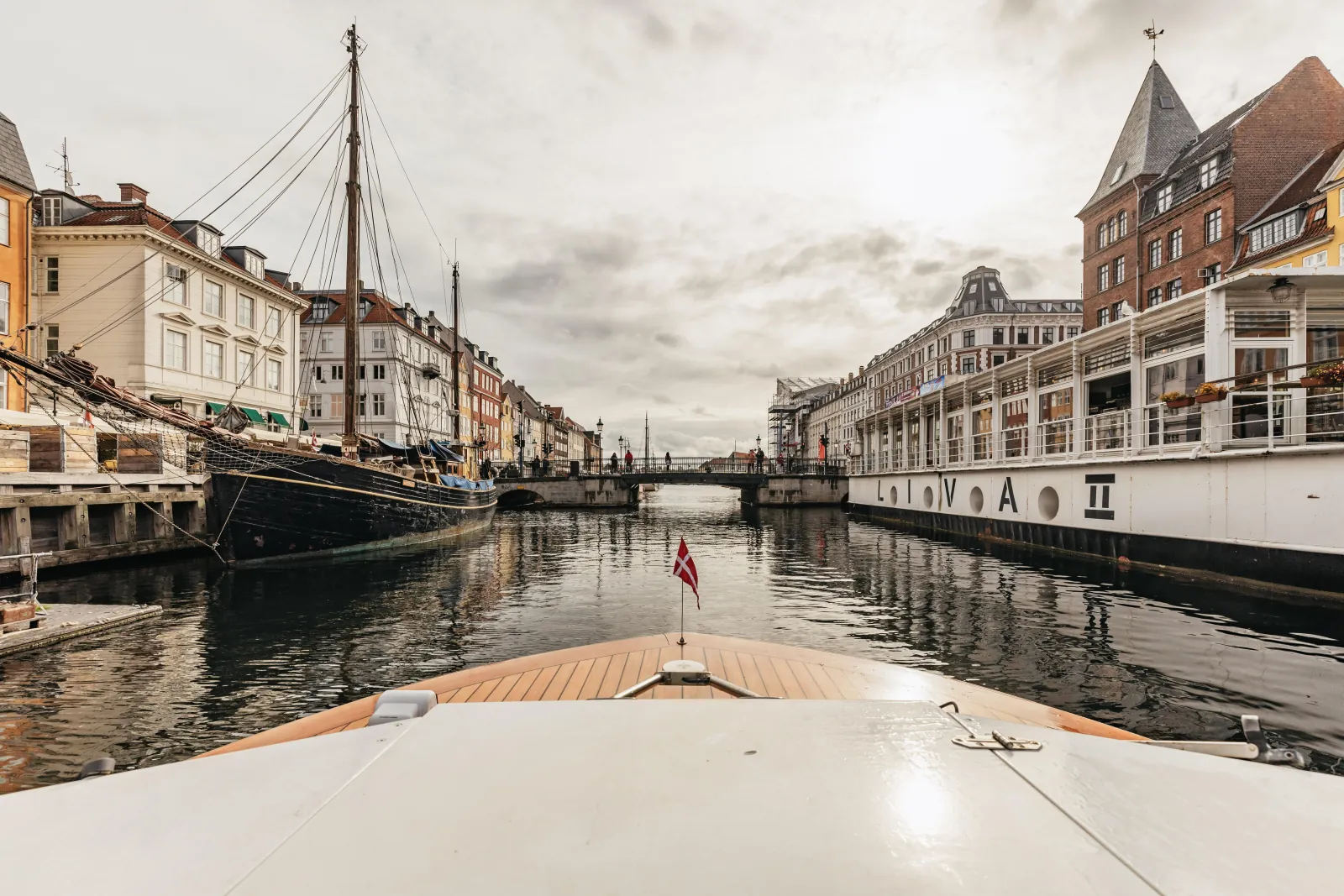 Old wooden sailing ships moored along Nyhavn, seen from the water