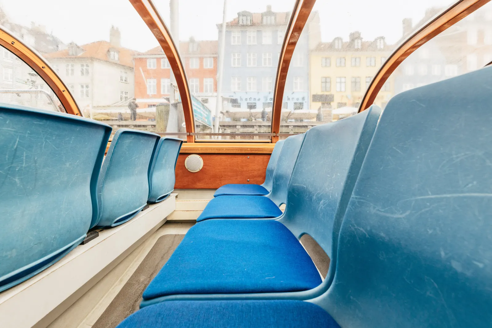 Rows of blue seats under the transparent roof of a canal boat