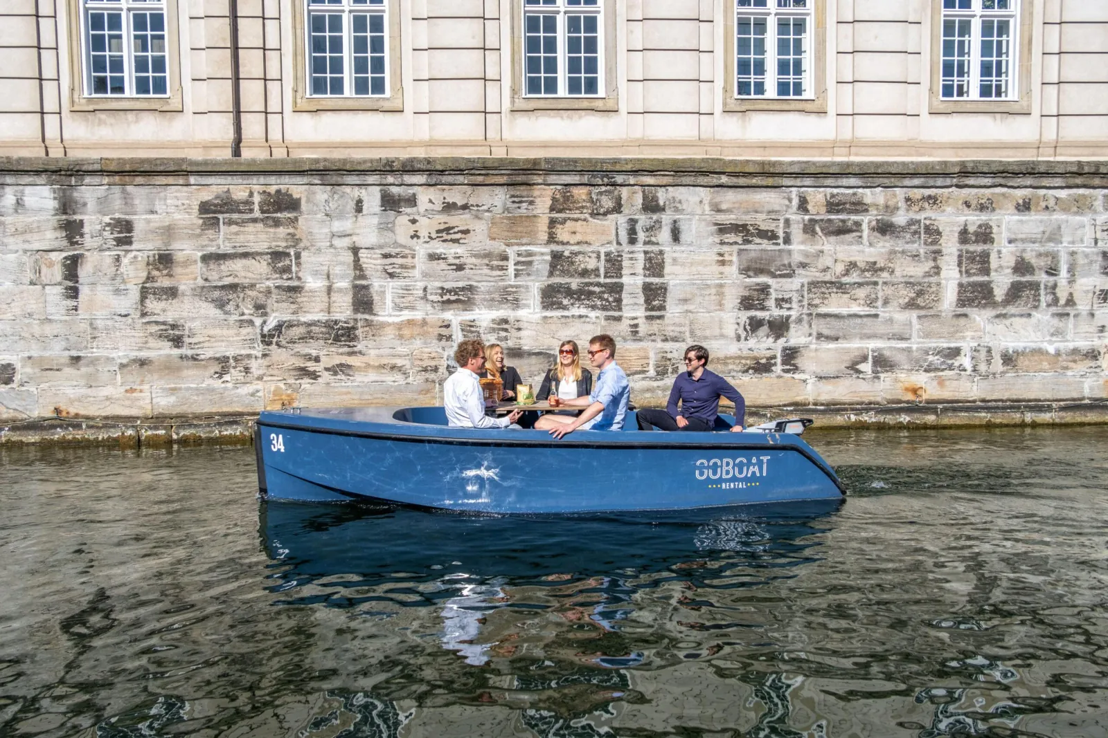 A blue GoBoat passing a stone embankment