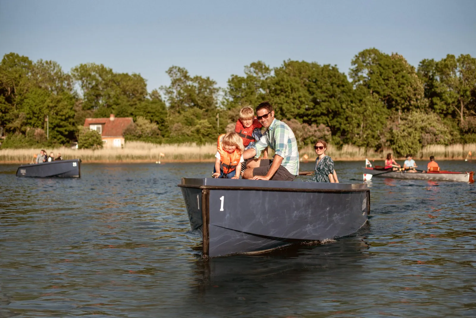 Two guests at the wheel of a GoBoat near a green bank