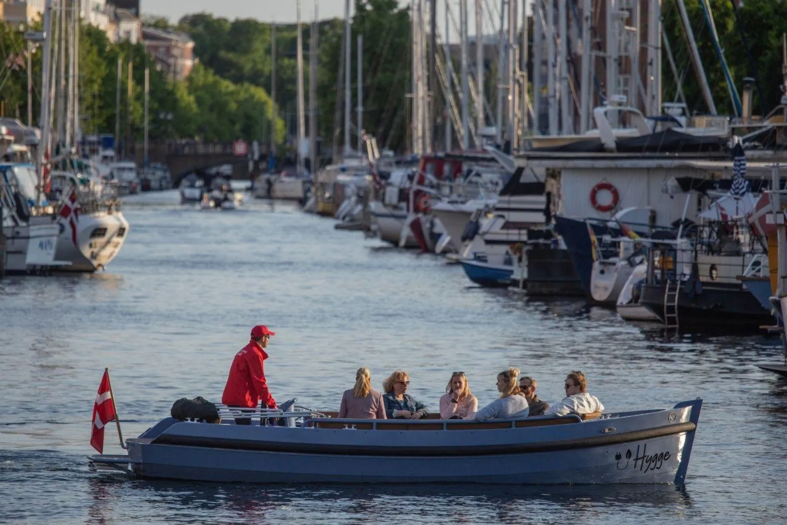 The boat flying a Danish flag between moored yachts