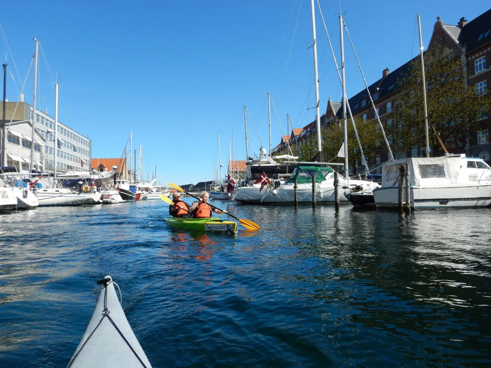 Kayaking past moored sailing boats in Christianshavn