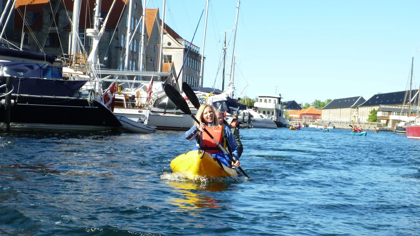 A kayaker paddling in front of old ships