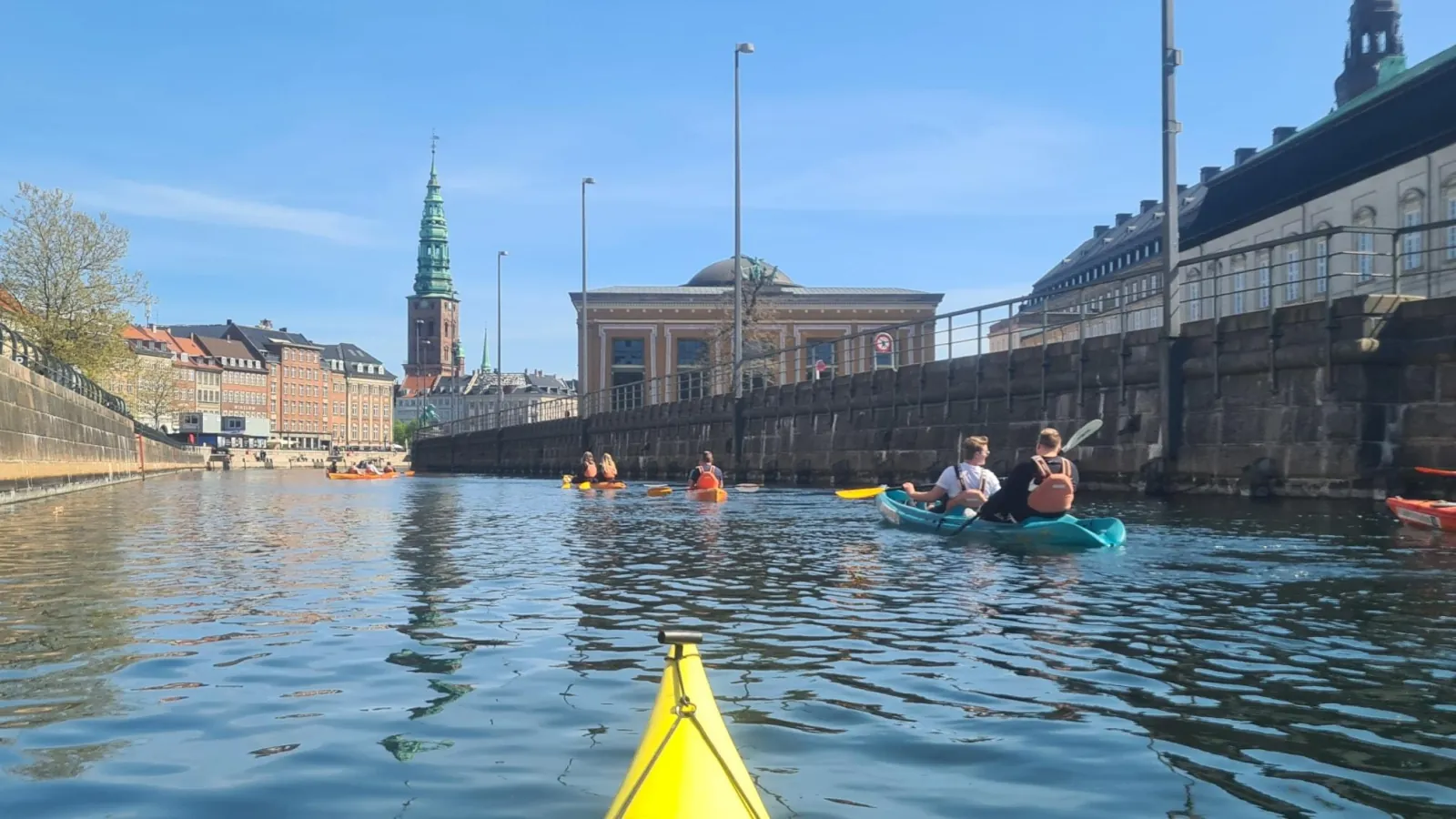Kayaks on a wide canal with Christiansborg's tower behind