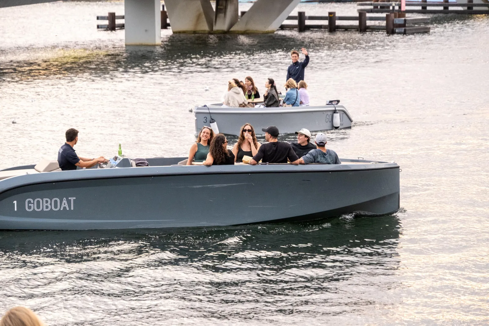 A grey GoBoat with guests on board passing under a bridge