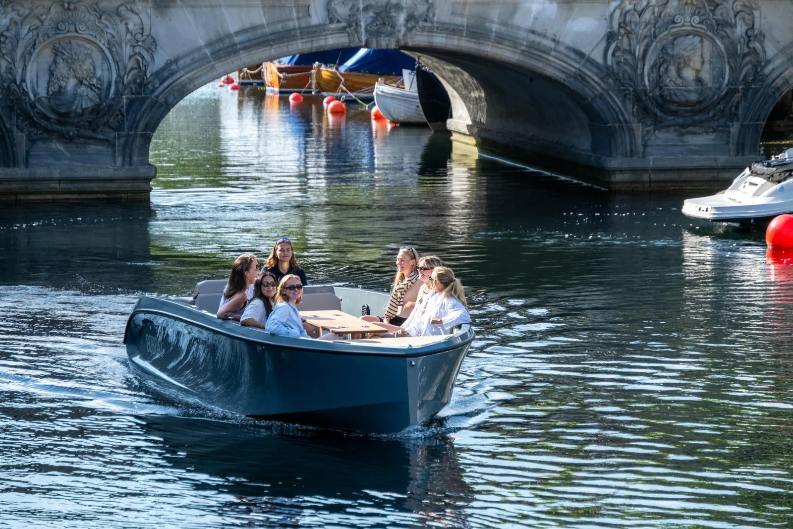 A GoBoat passing beneath a stone arch bridge