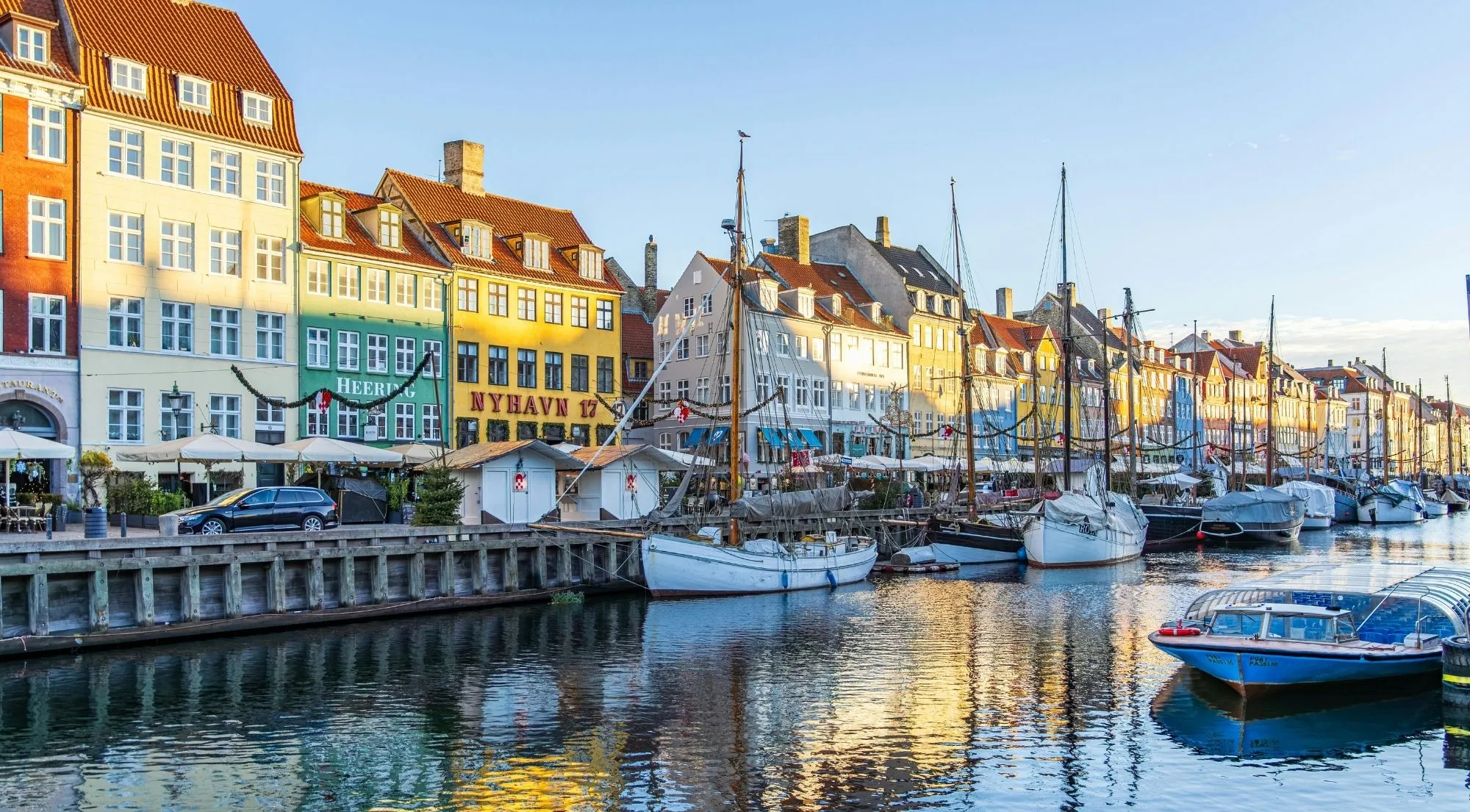 Small boats on calm water in front of Nyhavn's houses on a clear morning